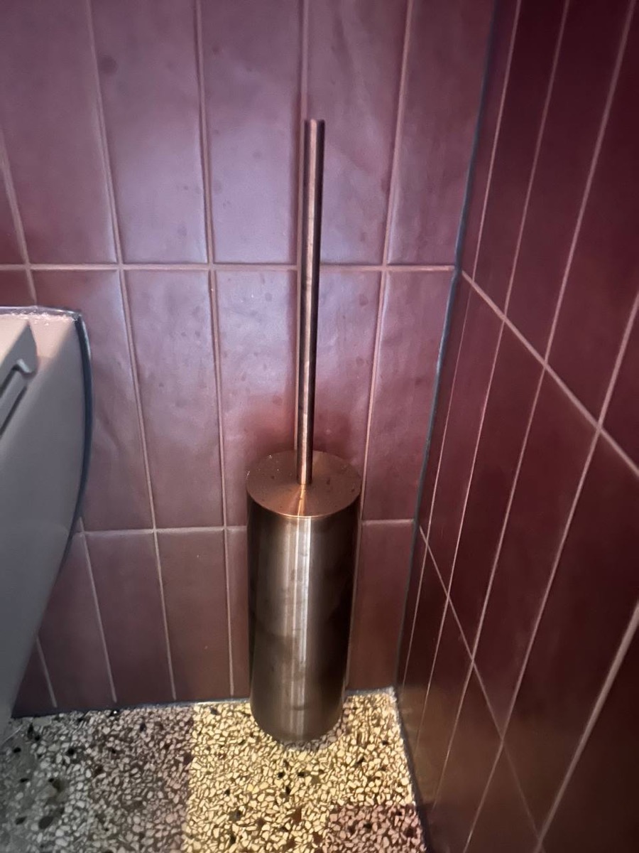 Detail toiletborstelhouder van Linki in mokka tegen bordeauxrode tegels