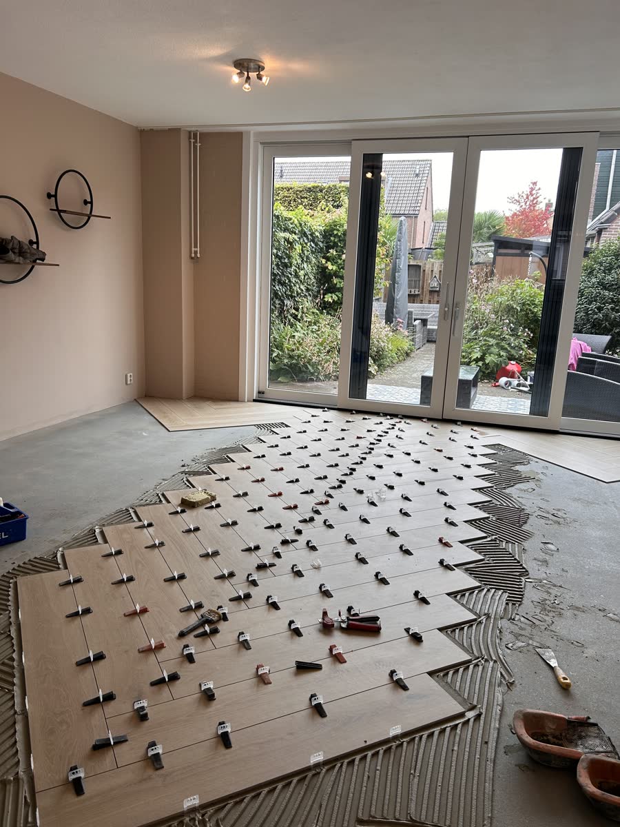 Eerste rijen keramische planken in de tegellijm, met nivelleerclips
