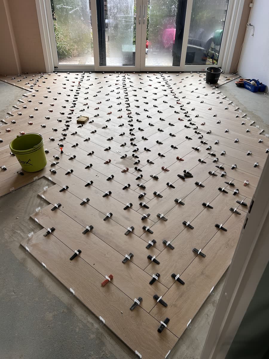 Visgraatvloer tijdens het leggen, met nivelleerclips en wiggen