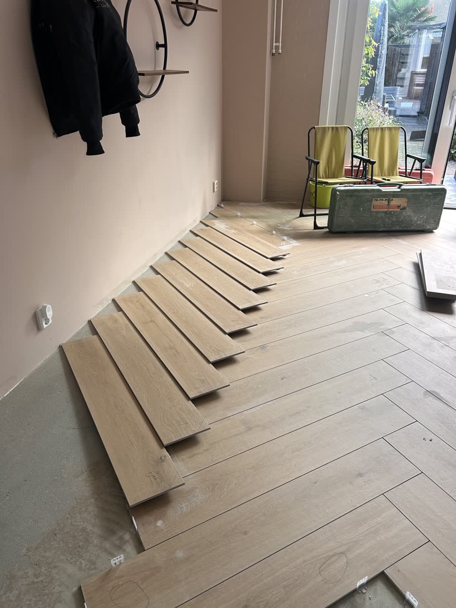 Op maat gezaagde planken langs de wand, klaar om te leggen
